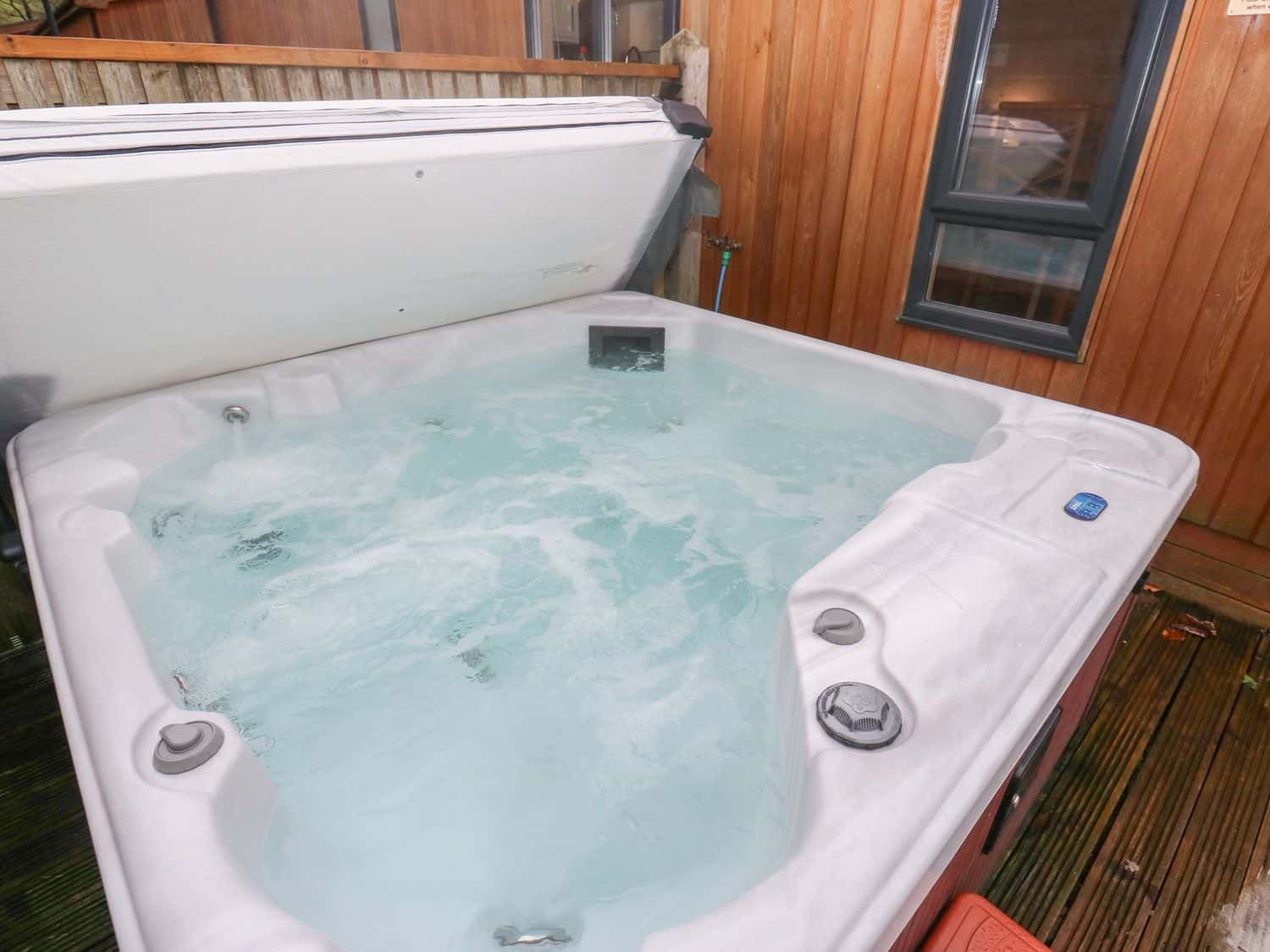 Large hot tub with moorland views on double veranda at Dovestone Secluded Lodge