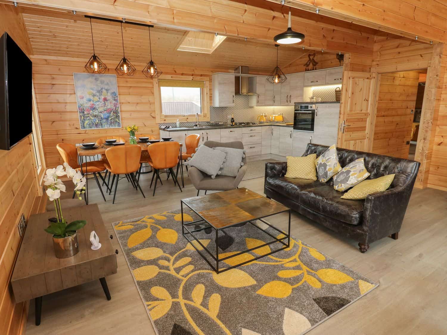 Open plan living space with wooden walls and modern furnishings at Height End Farm