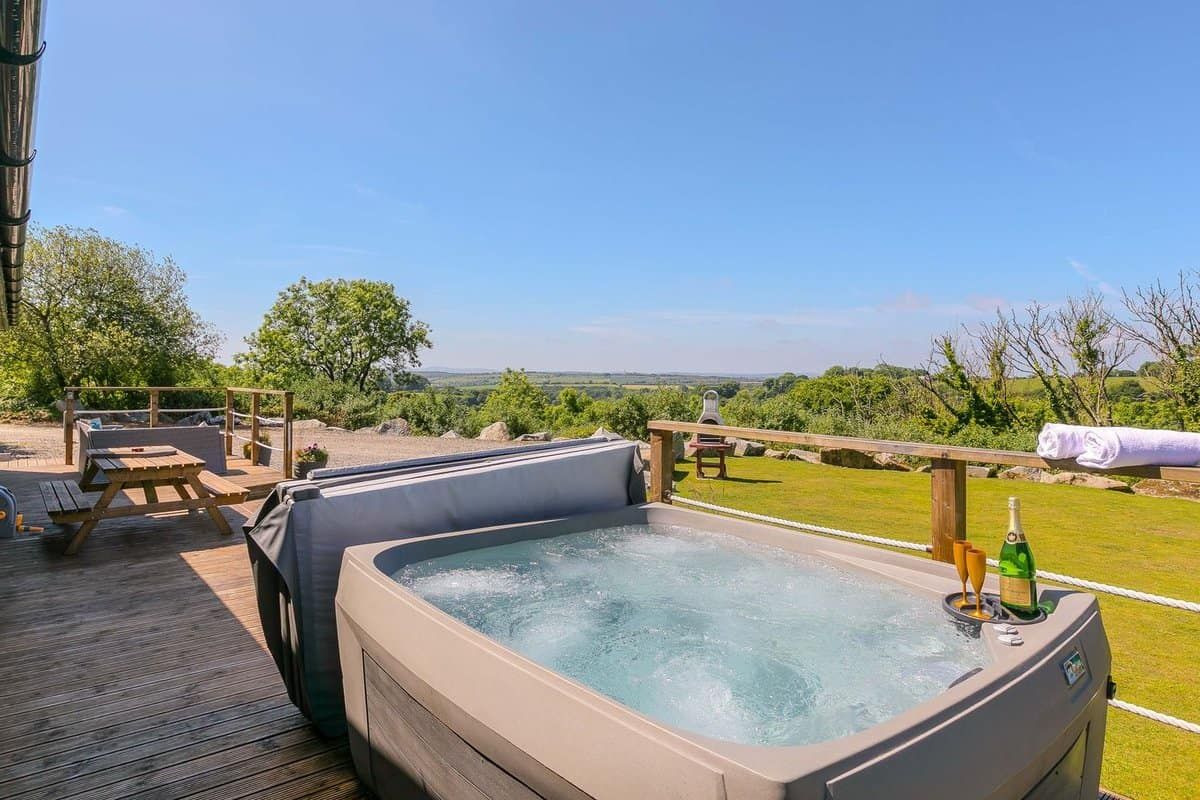 Private outdoor hot tub with peaceful garden views at Mellydonen