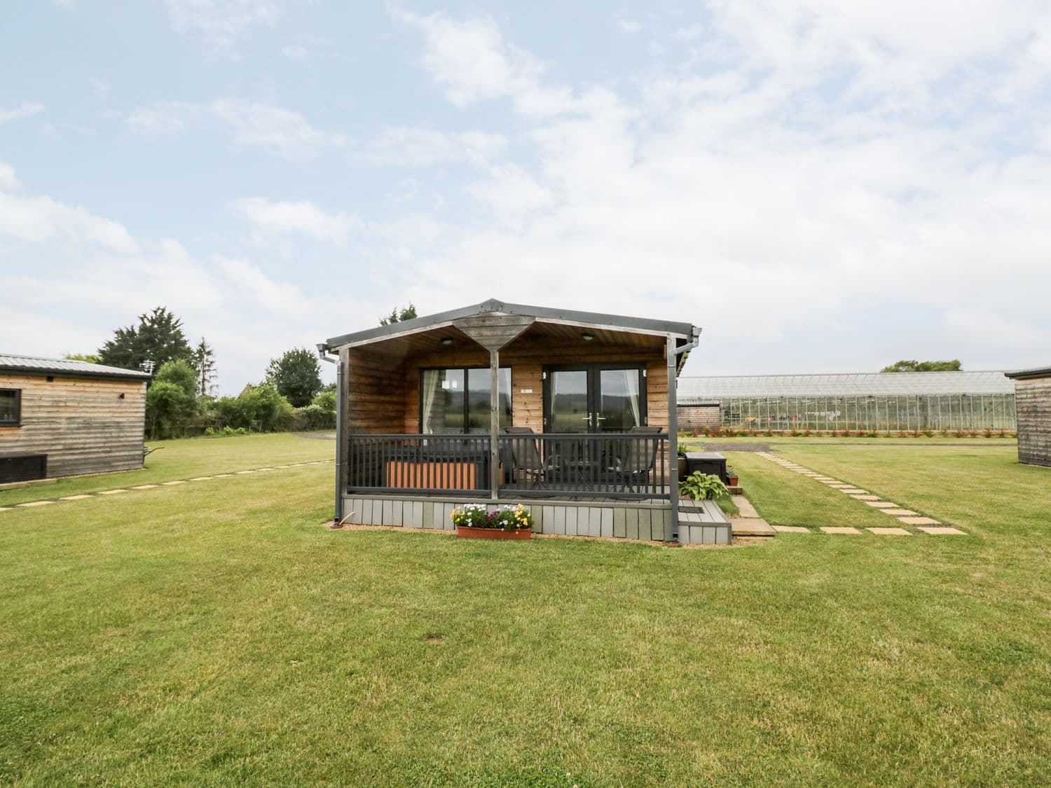 Cotswold View 3 cabin with small porch and railing on a sunny day