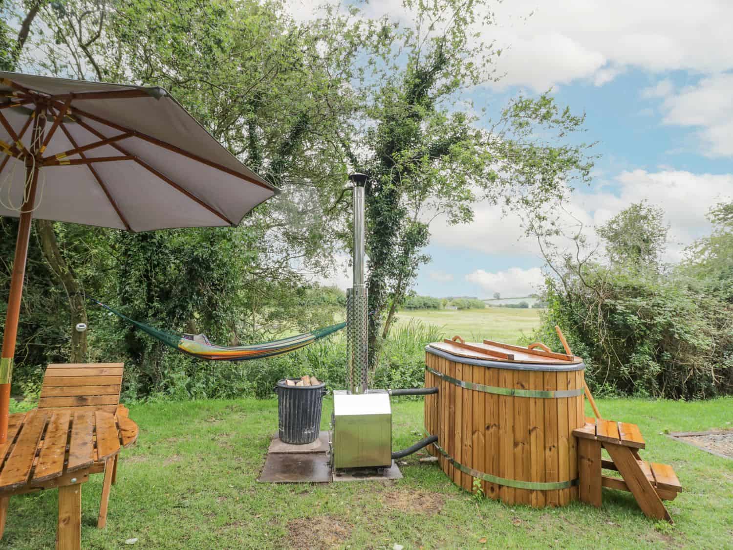 Outdoor garden area with wooden hot tub and hammock at Dragonfly