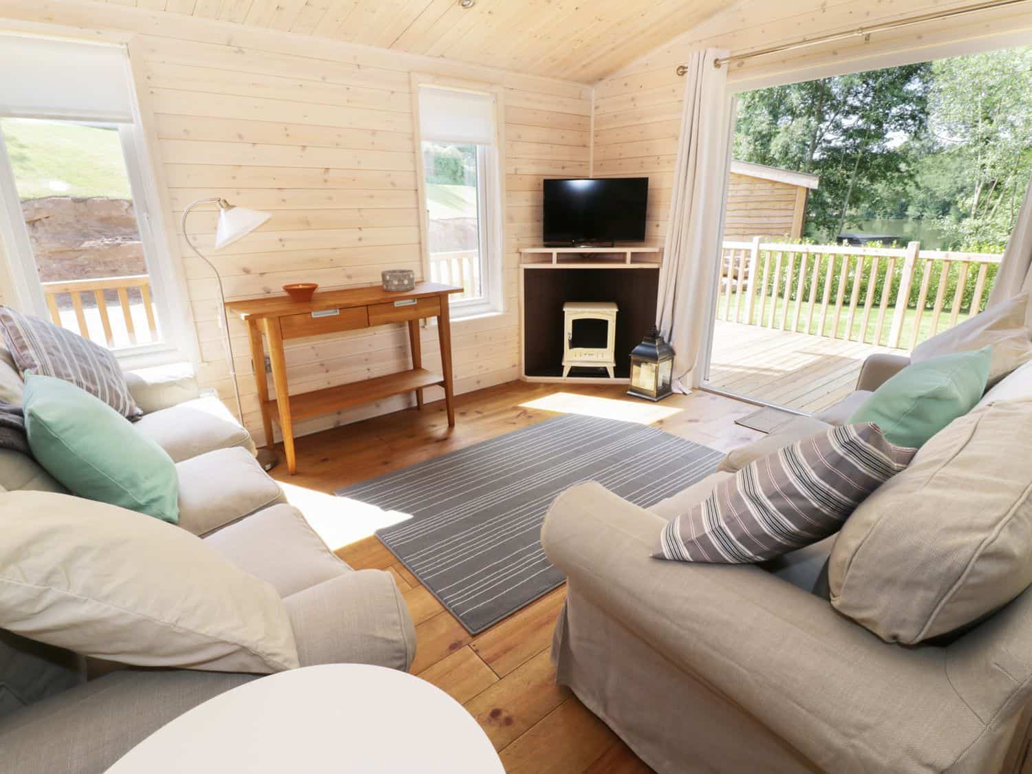 Cosy living room with sofas, cushions and wooden table at Kingfisher