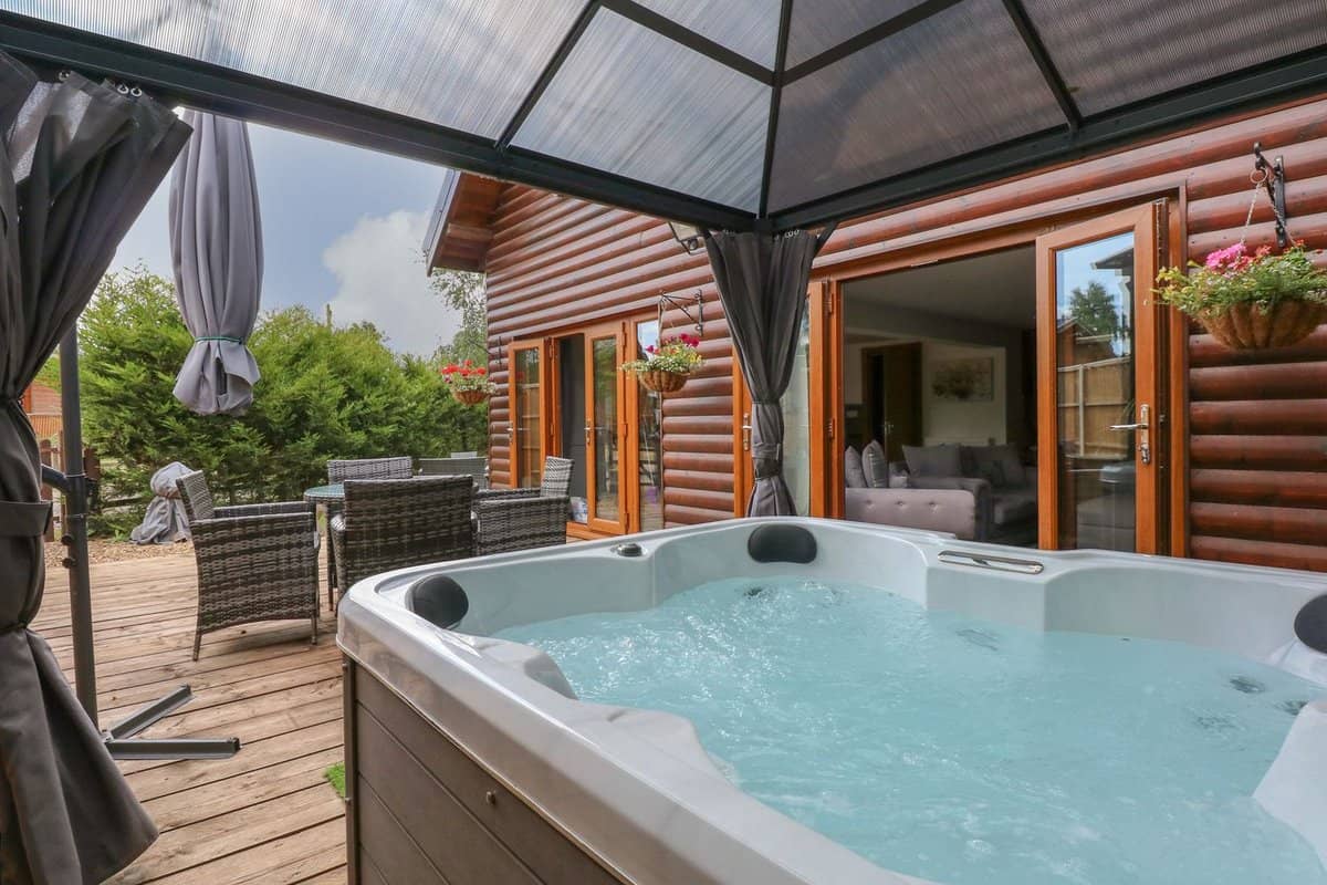 Private outdoor hot tub under gazebo surrounded by woodland at Little Lodge