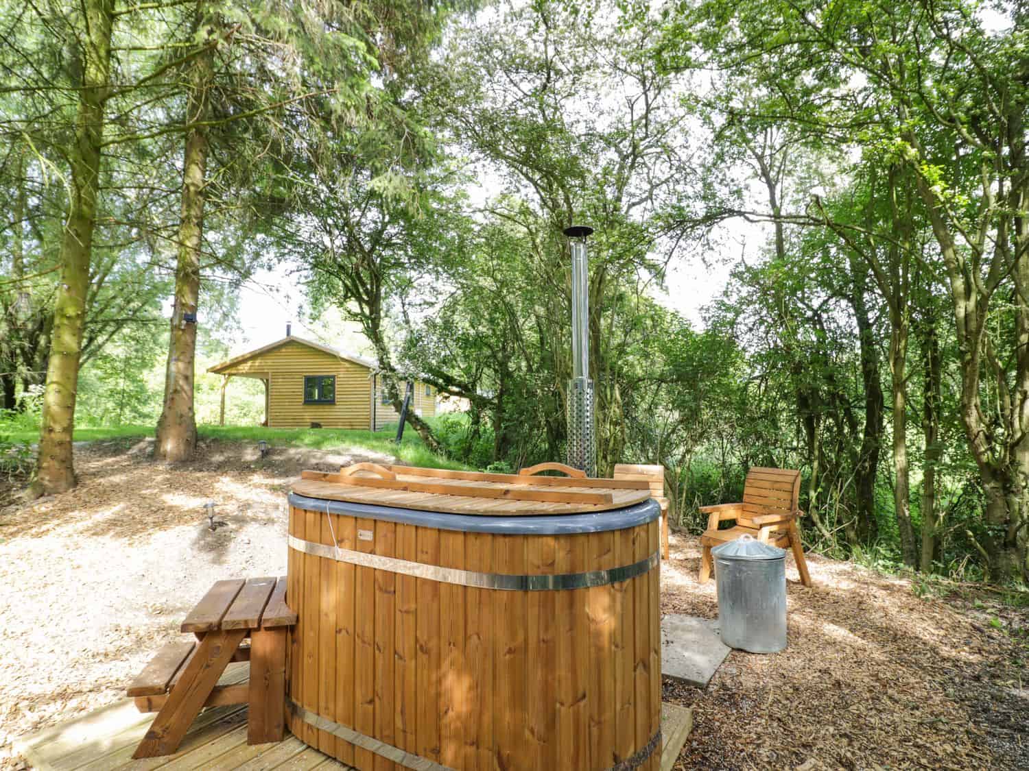 Outdoor area with wooden hot tub and wooden chair at Willow lodge